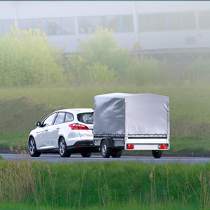 A car towing a trailer down the highway.